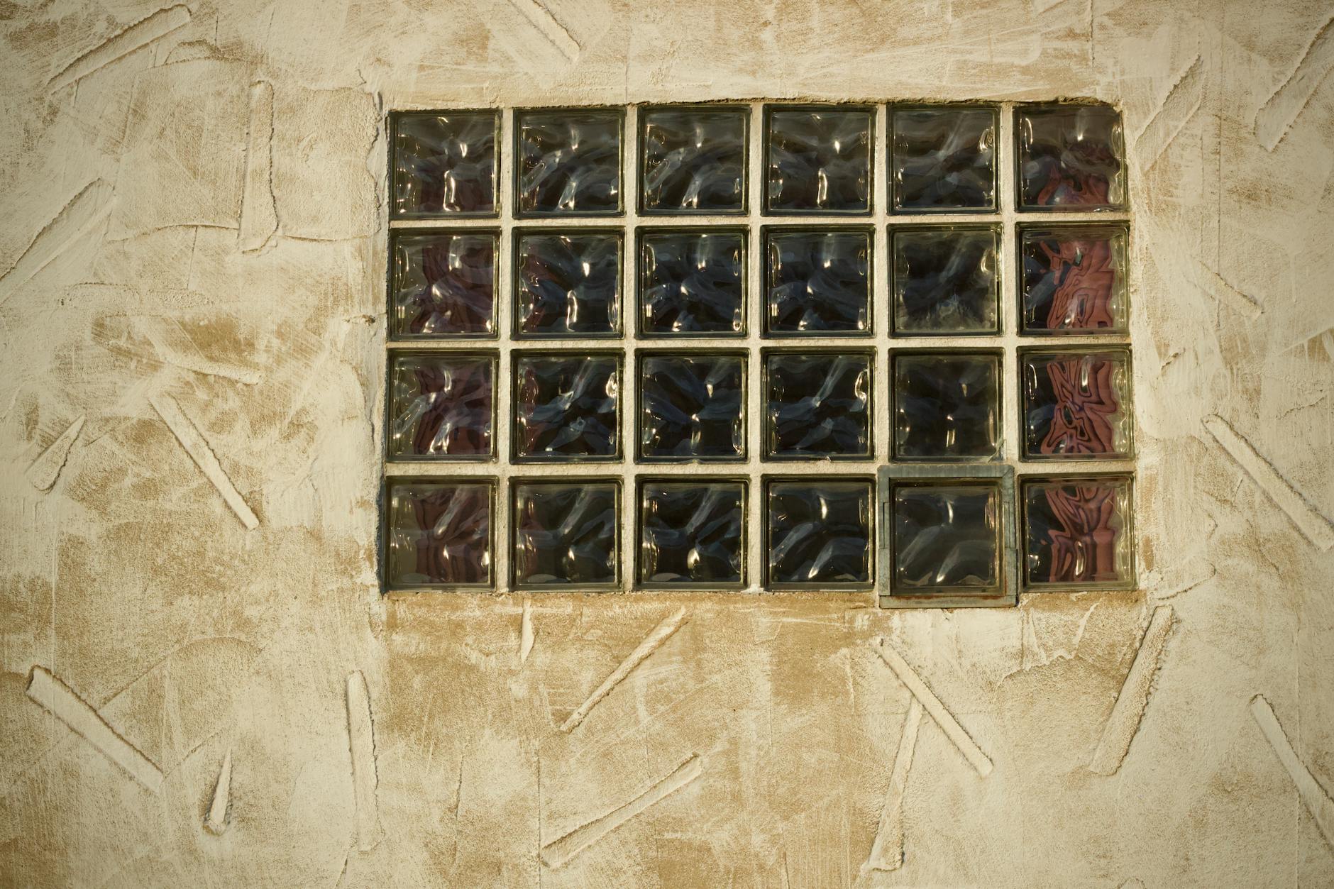 Szklany luksfer w beżowej ścianie tynkowanej jako dekoracyjny detal