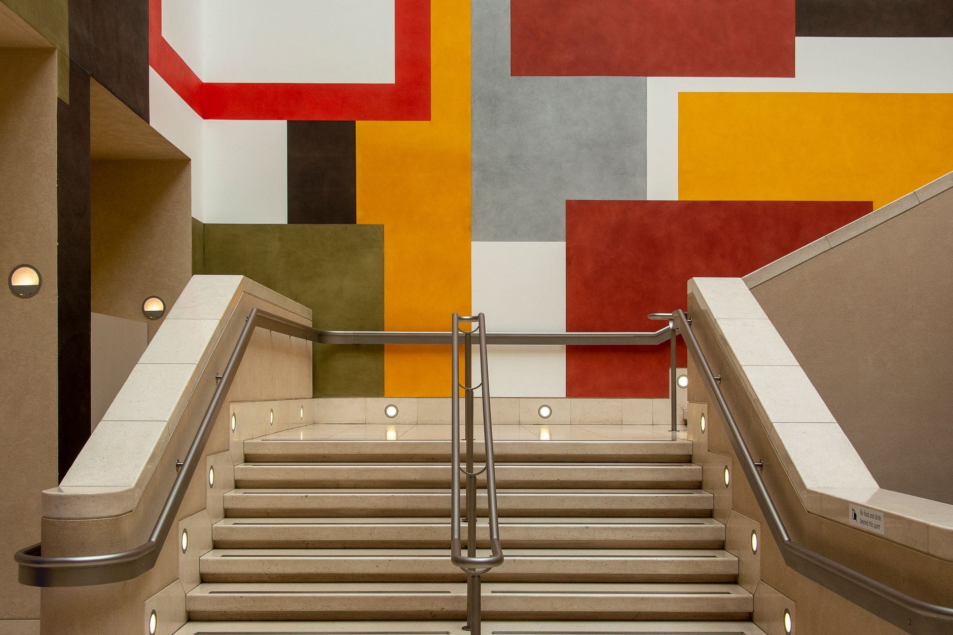 Schody wewnętrzne z kolorową geometryczną galerią na ścianie