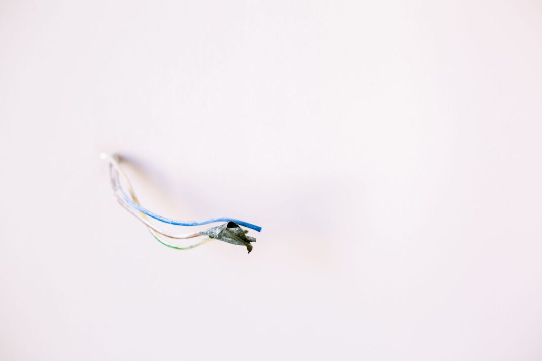 Luźne przewody elektryczne wystające z białej ściany Luźne przewody elektryczne wystające z białej ściany